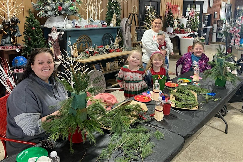 Group of people decorating trees in a room with Christmas decorations.